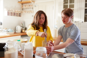 photo of woman helping young man to bake